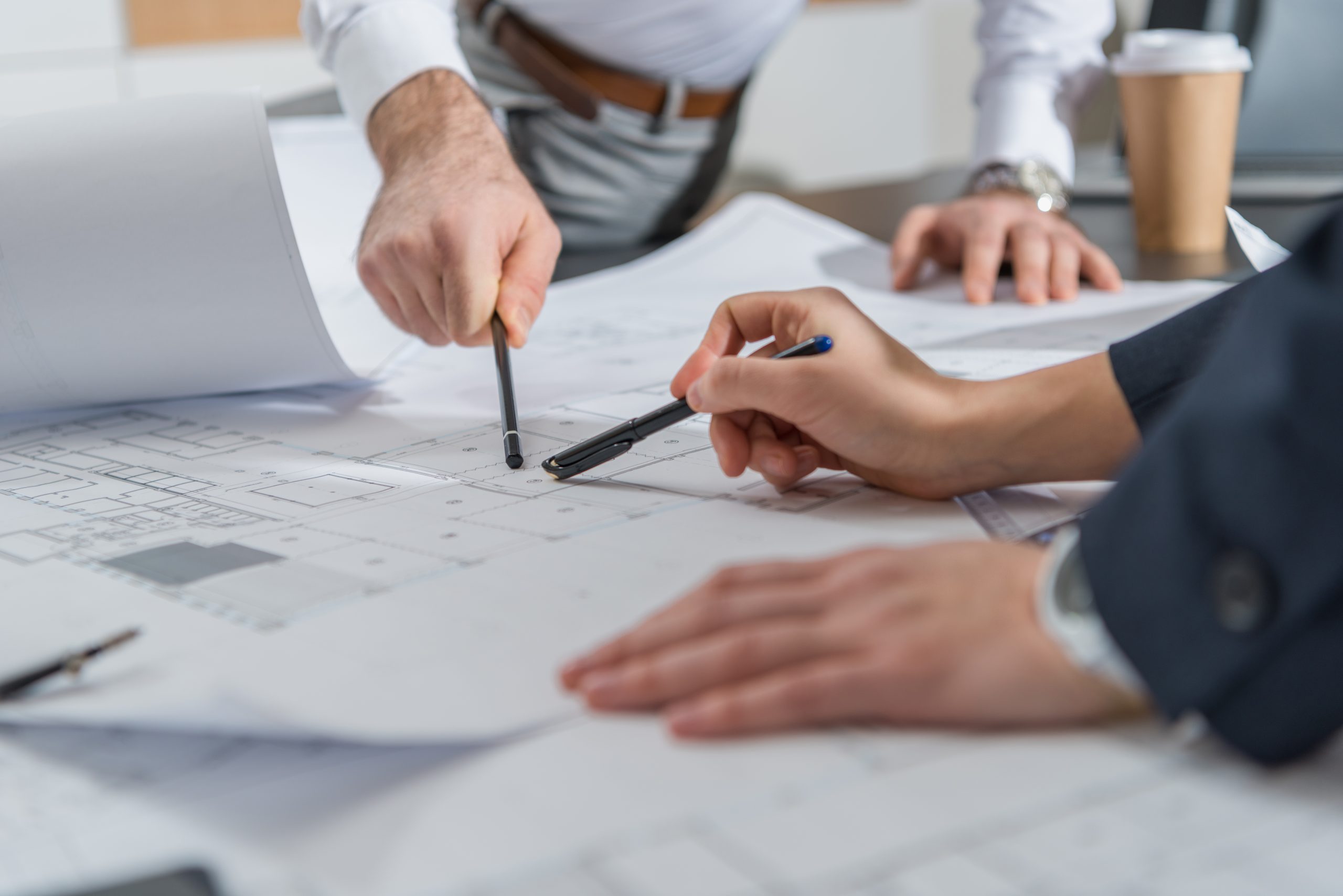 cropped shot of architects working with building plans together at office